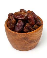 dried dates in wooden bowl isolated on white