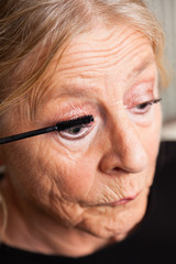 Good looking senior woman doing make-up.