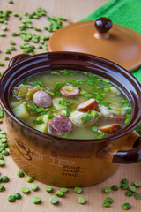 Pea soup with smoked sausages in a pot