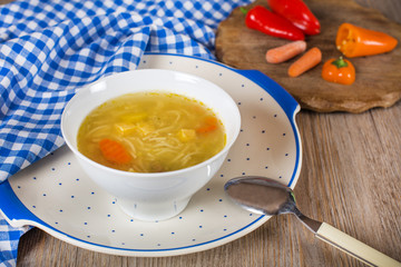 Noodle soup with carrots and vegetables in white bowl