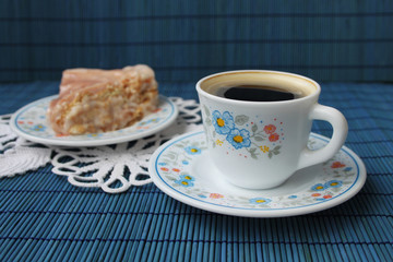 Cup of coffee and biscuit cake on blue background