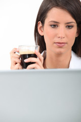 Woman drinking coffee while working at her laptop