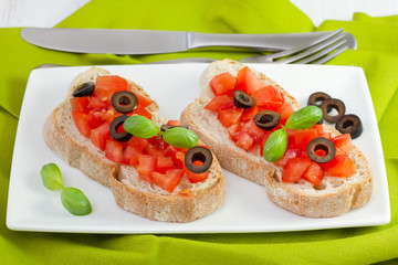 toasts with tomato ans olives on the plate