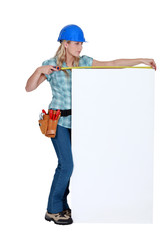 Construction worker measuring a blank board