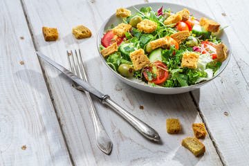 Fresh salad with croutons and chicken on an old table