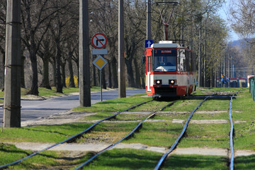 Fototapeta na wymiar Czerwony tramwaj elektryczny działa poprzez zniszczonych szyn.