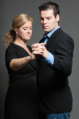 Stylish happy young couple dancing. Studio shot against grey.