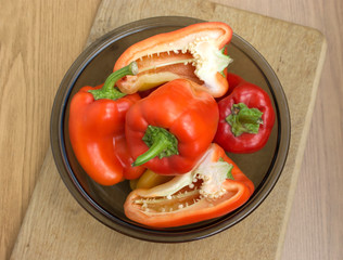 Many red and orange sliced and whole peppers in a bowl