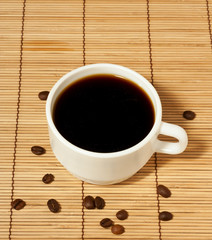 White coffee cup with coffee beans on the table