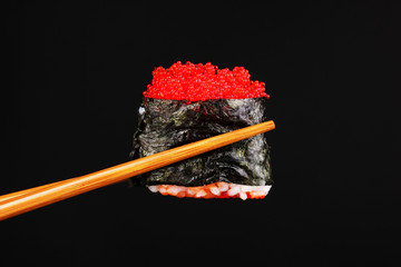 holding sushi with chopsticks isolated on black