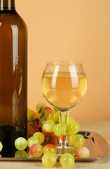 White wine in glass with bottle on salver on beige background