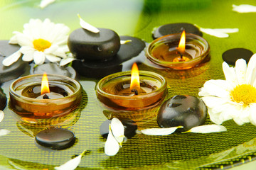 spa stones with flowers and candles in water on plate