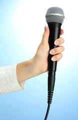 female hand with microphone, on blue background