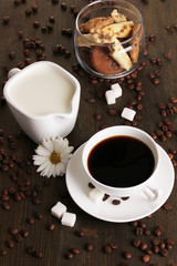 A cup of strong coffee and sweet cream on wooden table close-up