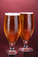 Glasses of beer on pink background