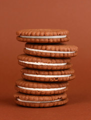 Chocolate cookies with creamy layer on brown background