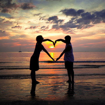 Young couple holding heart-shaped on the beach