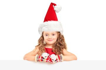 A small girl with santa hat posing behind a panel