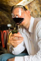 Mann testet Wein im Hintergrund Weinfässer