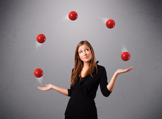 young girl standing and juggling with red balls - obrazy, fototapety, plakaty