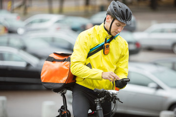 Male Cyclist With Courier Bag Using Mobile Phone On Street