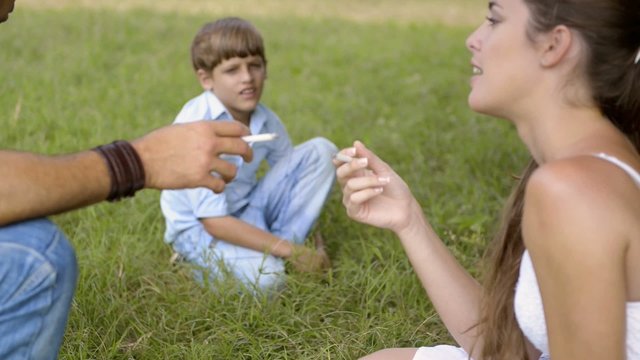Little boy looking at parents smoking cigarette and talking