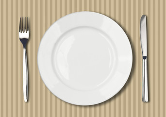 round white plate, knife and fork on wooden table