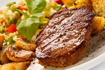Grilled steak, baked potatoes and vegetables