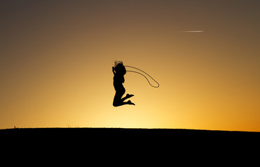 silhouetted girl rope skipping in sunset