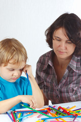 Little blond boy with his mother draws with color pencils