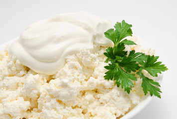 Cottage cheese in the bowl with sour cream and parsley isolated