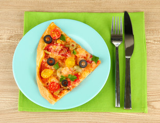 plate with a slice of delicious pizza on wooden background