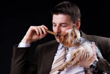 Young businessman sitting on the sofa with a cigar and a dog