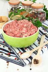 Bowl of raw ground meat with spices on wooden table