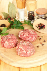 Raw meatballs with spices on wooden table