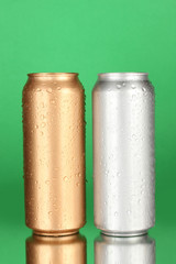 Aluminum cans with water drops on color background