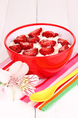 Cottage cheese in red bowl with sliced strawberries