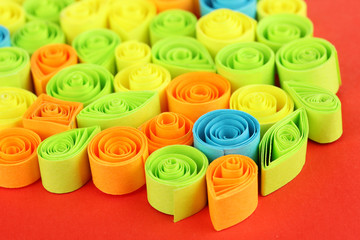 Colorful quilling on red background close-up