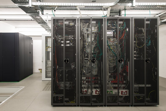 backside of arranged black server racks in small computer room