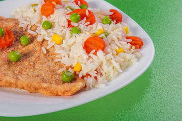 Close-up chicken fillet with side dish of rice and vegetable