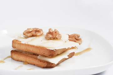 toast with cheese, nuts and honey, on white plate