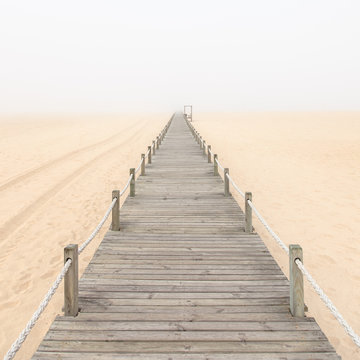 Fototapeta Drewniany kładka na tle mglisty piasek na plaży. Portugalia.