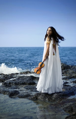 Fototapeta na wymiar young attractive woman playing violin on sea background