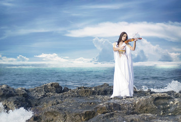 young attractive woman playing violin on sea background