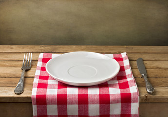 Empty plate on wooden table over grunge background