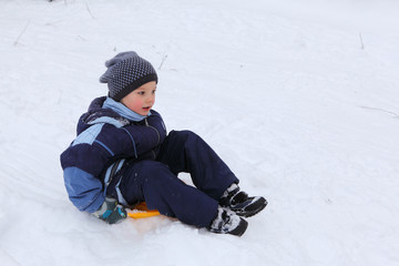 Fototapeta na wymiar Little boy sliding from an ice slope