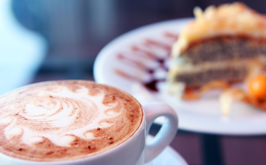 Cappuccino and poppy seed cake on cafe table.