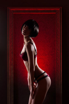 A young and sexy woman posing in dark red erotic lingerie