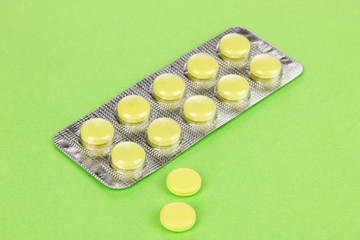 Pills packed in blister on green background