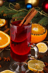 Fragrant mulled wine in glass with spices and oranges around